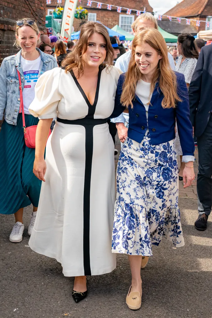 Princess Beatrice (R) and Princess Eugenie (L) walk together, smiling, at a Coronation Big Lunch in Chalfont St Giles.