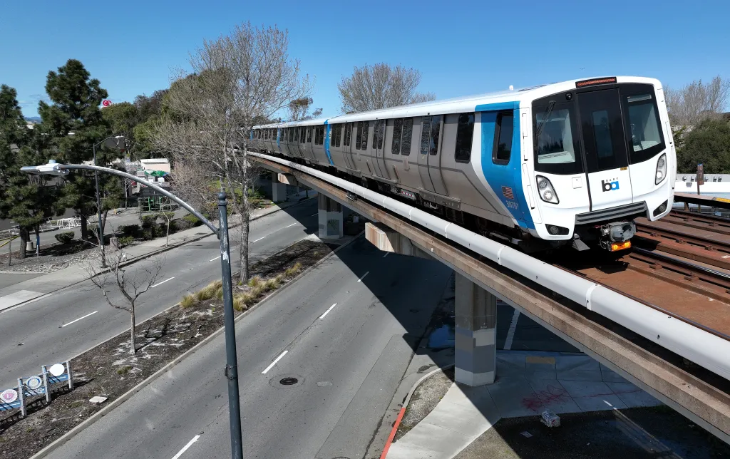 A BART train on elevated tracks approaches El Cerrito Plaza station.