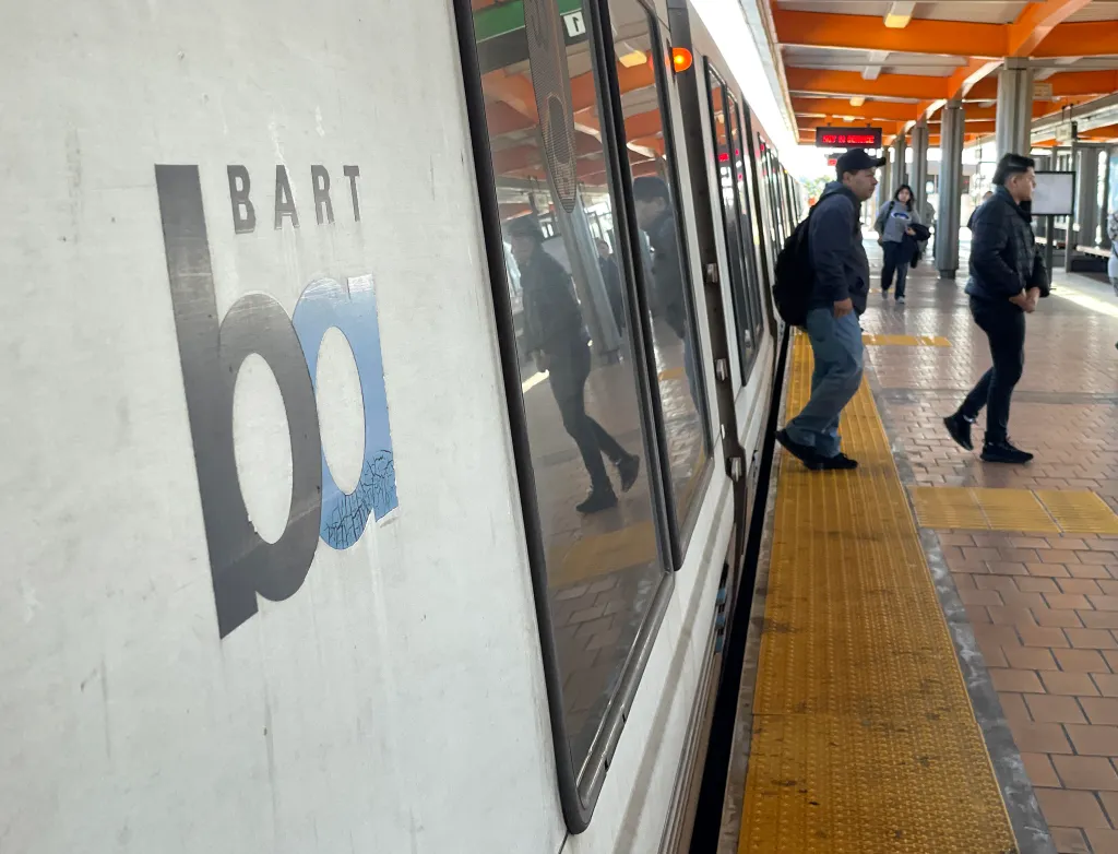 Passengers getting off a BART train at a station.