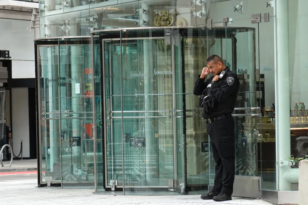 A security guard standing in front of a Neiman Marcus store, symbolizing the struggles of downtown San Francisco's retail sector.