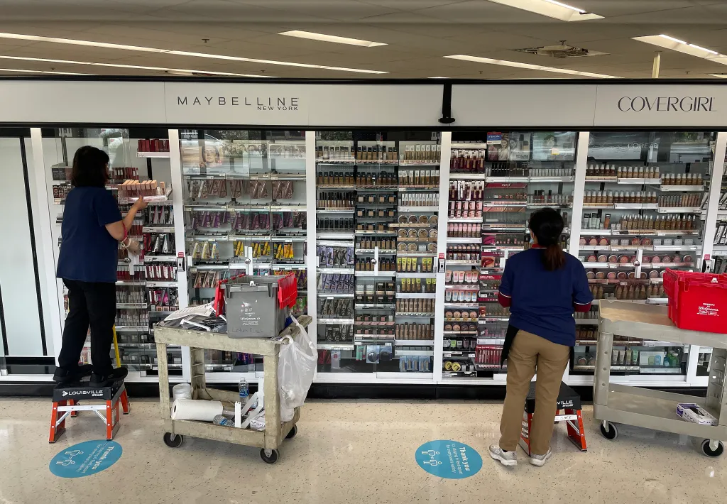 Walgreens workers stocking merchandise in locked security cabinets in the beauty aisle.