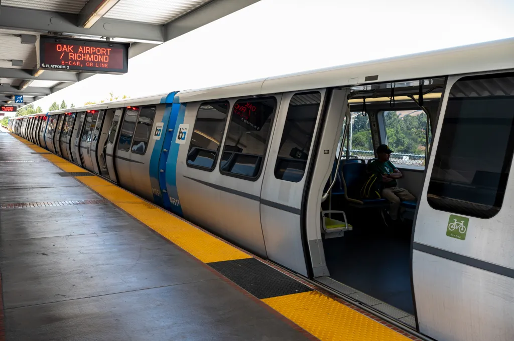 A BART train stopped at a station with a sign overhead displaying 