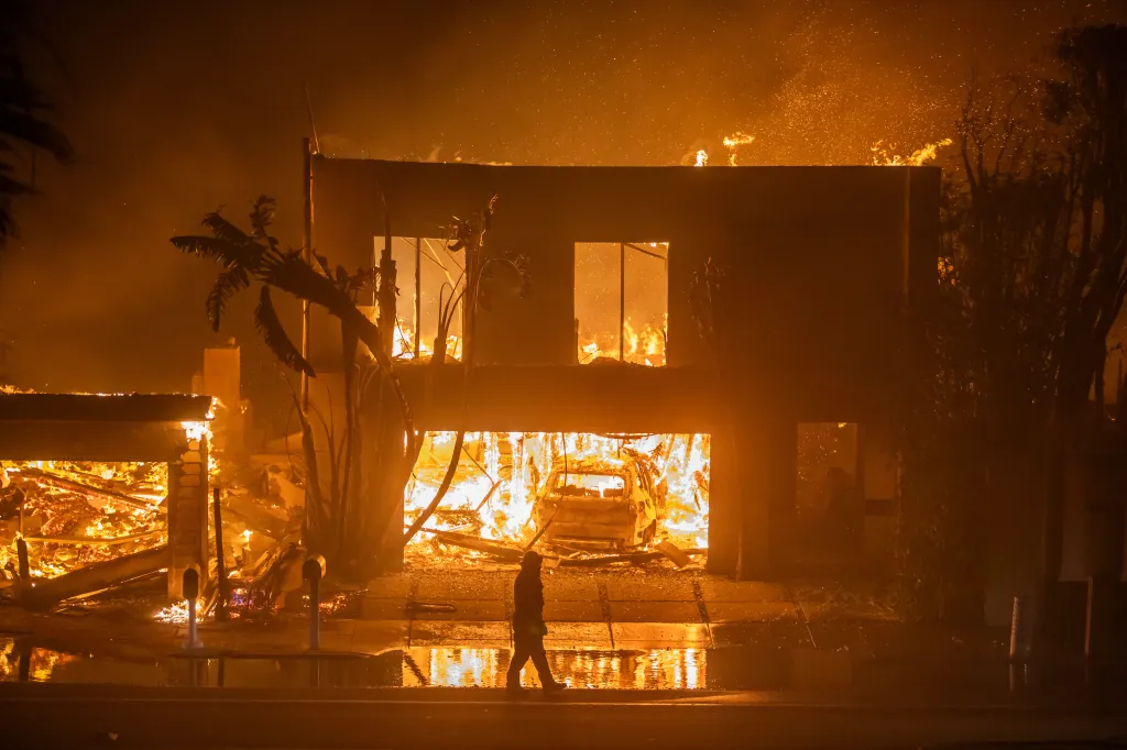 A firefighter watches a home burning down during the Palisades Fire in Los Angeles, California.