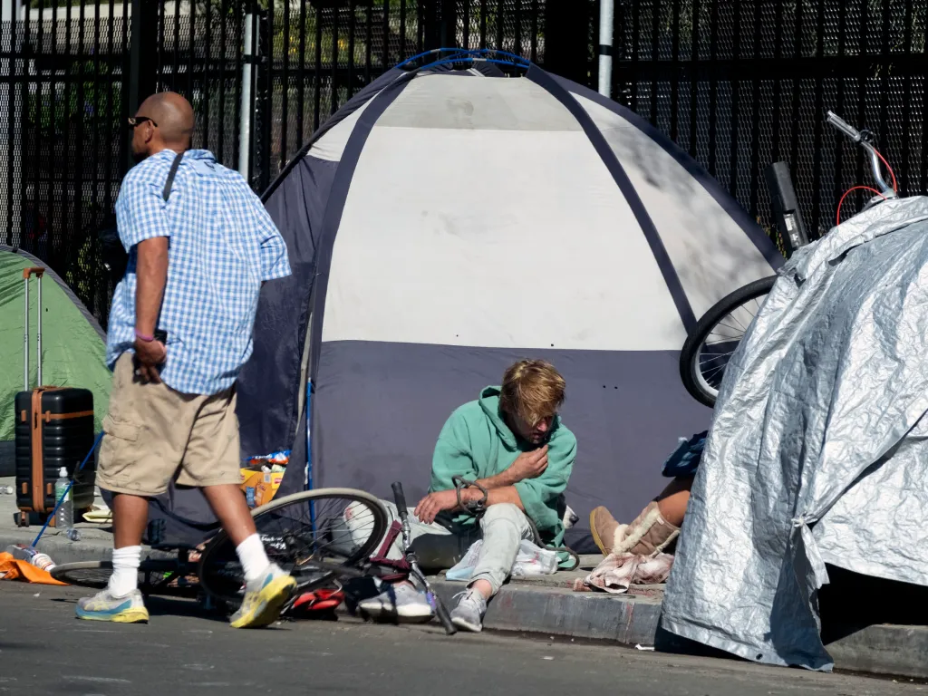Homeless encampment in Santa Monica, with tents on the sidewalk and two men near them.