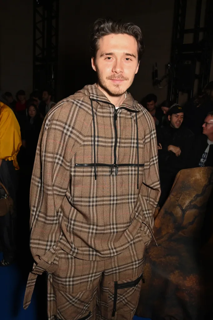 Brooklyn Beckham wearing a brown plaid hoodie and matching pants.