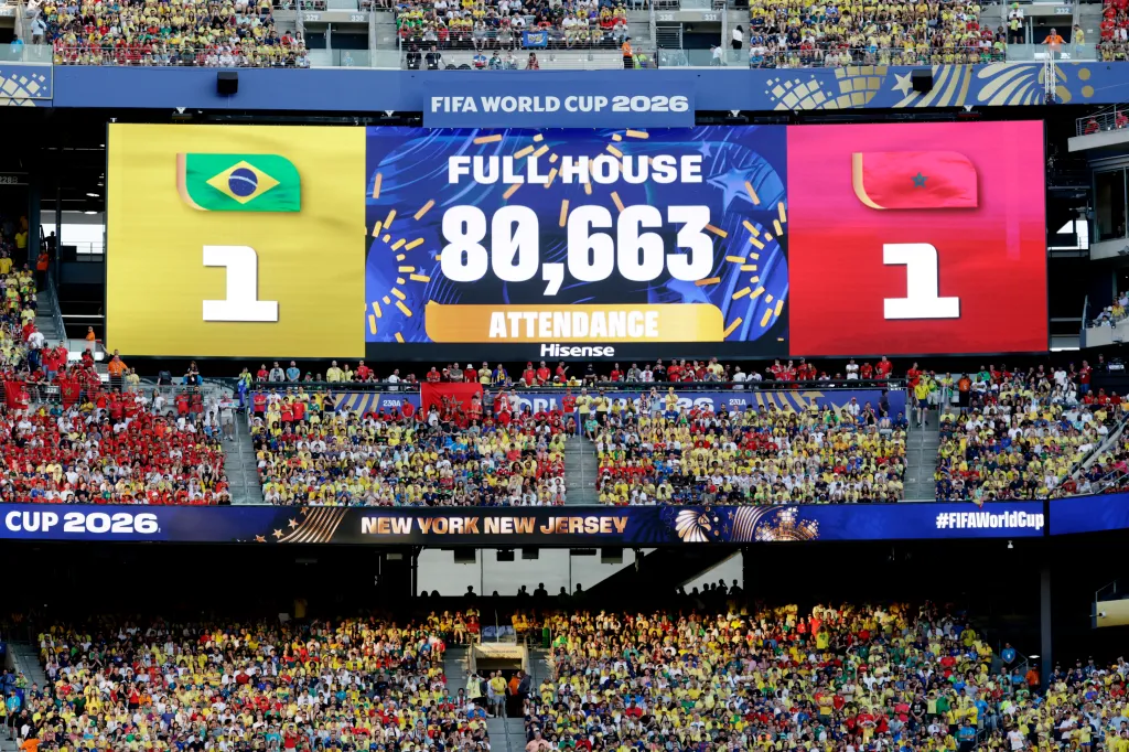 A FIFA World Cup 2026 score screen shows Brazil 1, Morocco 1, and an attendance of 80,663 in a stadium full of fans.