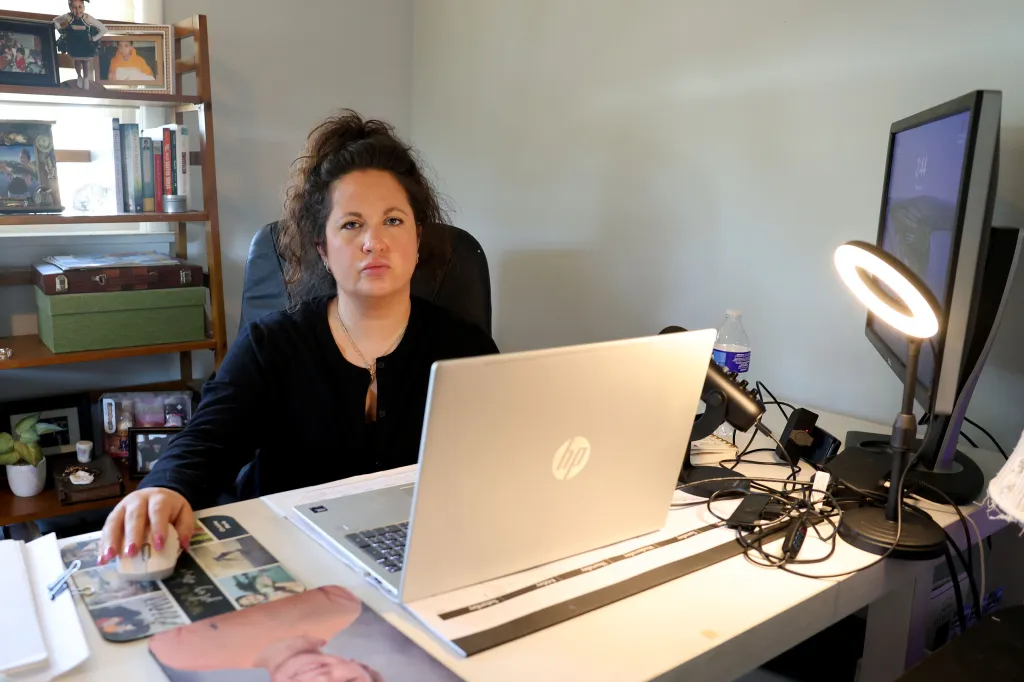 Christine Russo sitting at her desk, with a laptop and computer monitor, preparing for an interview.