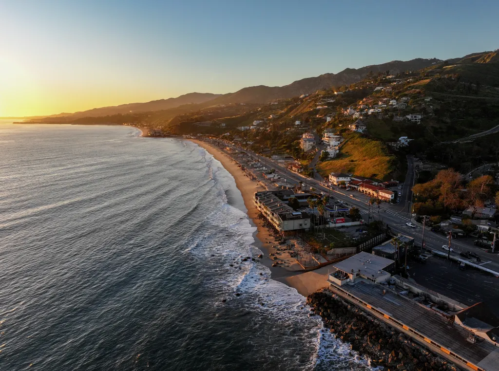 Aerial view of Malibu beachfront homes and Pacific Coast Highway after the Palisades Fire.