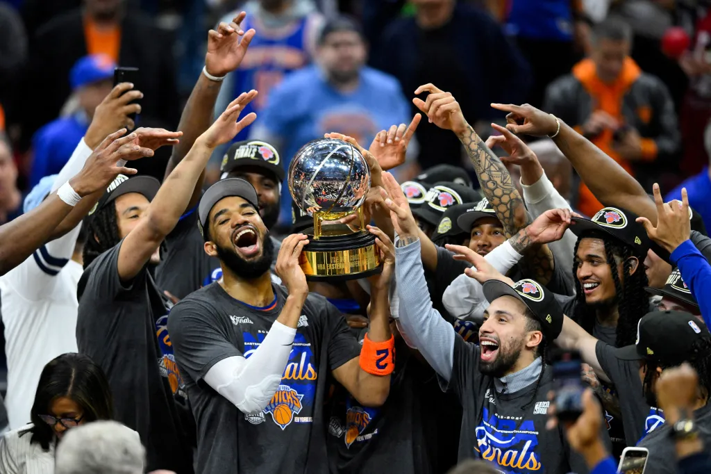 New York Knicks center Karl-Anthony Towns lifts the 2026 Eastern Conference trophy with teammates.