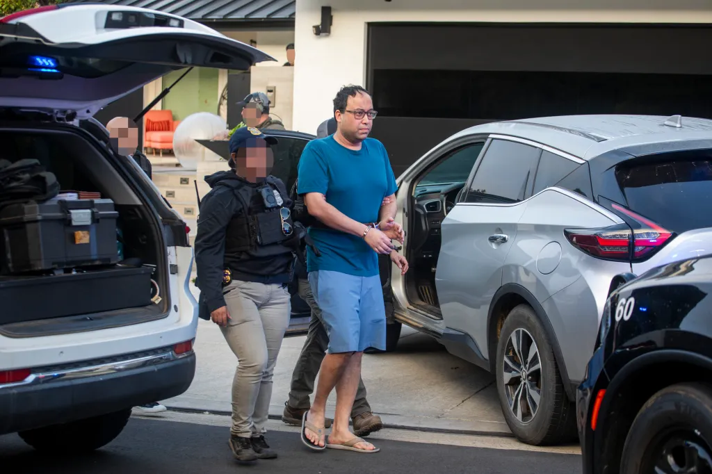 Law enforcement officers detaining a handcuffed man during a raid.