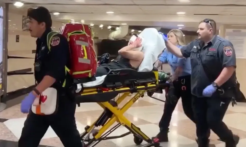 Emergency personnel transport a stabbing victim on a stretcher through Penn Station.
