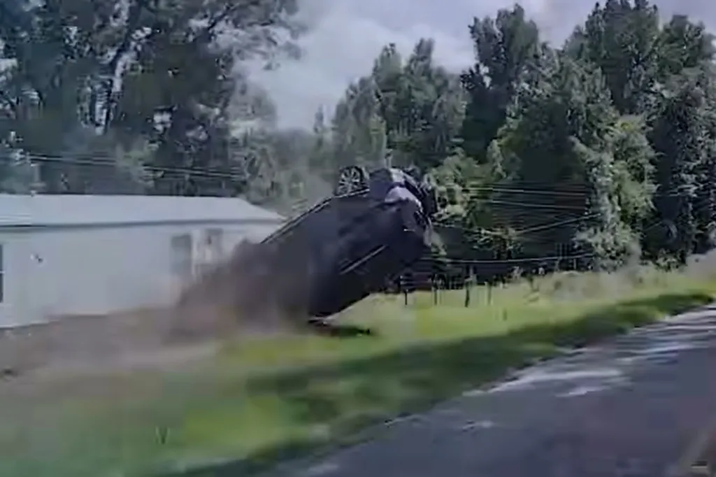 SUV skidding off a highway and rolling over, with a cloud of dust.