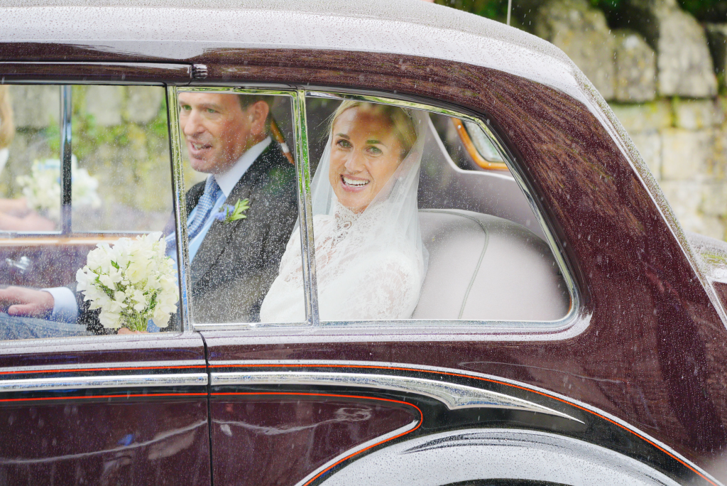 Harriet Sperling and Peter Phillips smiling in the back of a vintage car after their wedding.