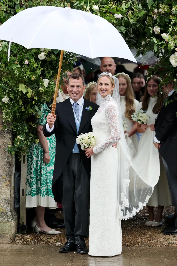 Peter Phillips and Harriet Sperling leaving their wedding ceremony under a white umbrella.