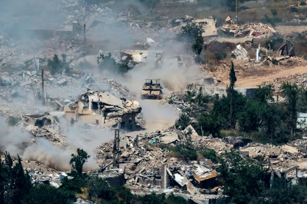 Israeli Merkava tanks drive along a road next to destroyed buildings on June 17, 2026.