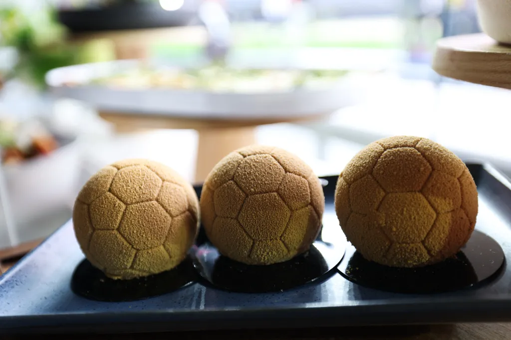 Three soccer ball-shaped desserts on a platter.