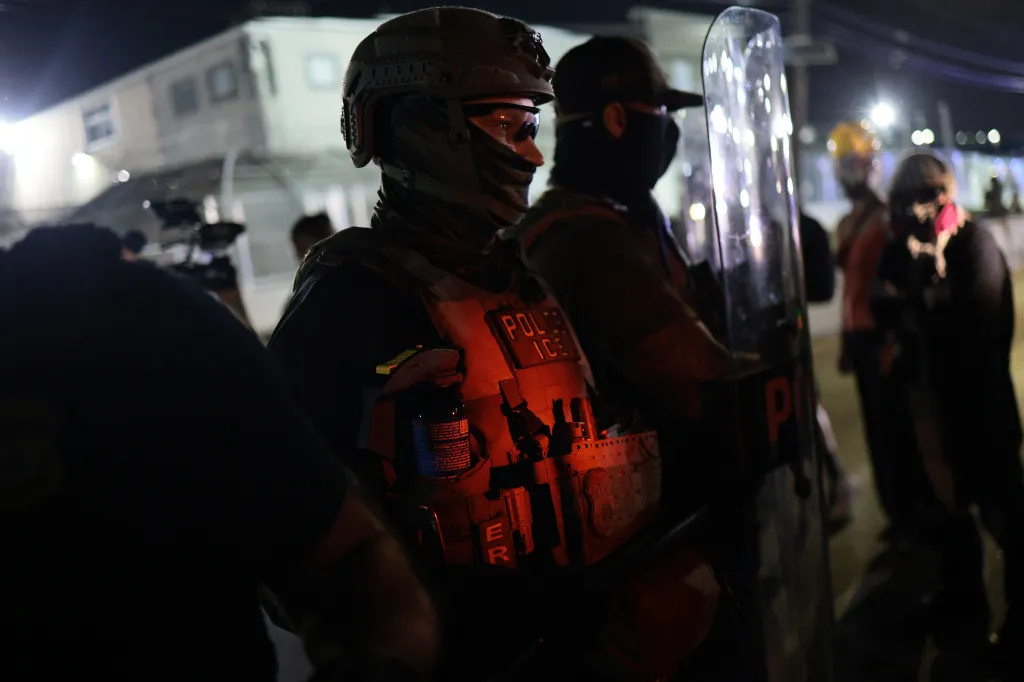 Homeland Security Investigations (HSI) and Immigration and Customs Enforcement (ICE) agents stand guard against protesters outside of Delaney Hall Immigration Detention Center.