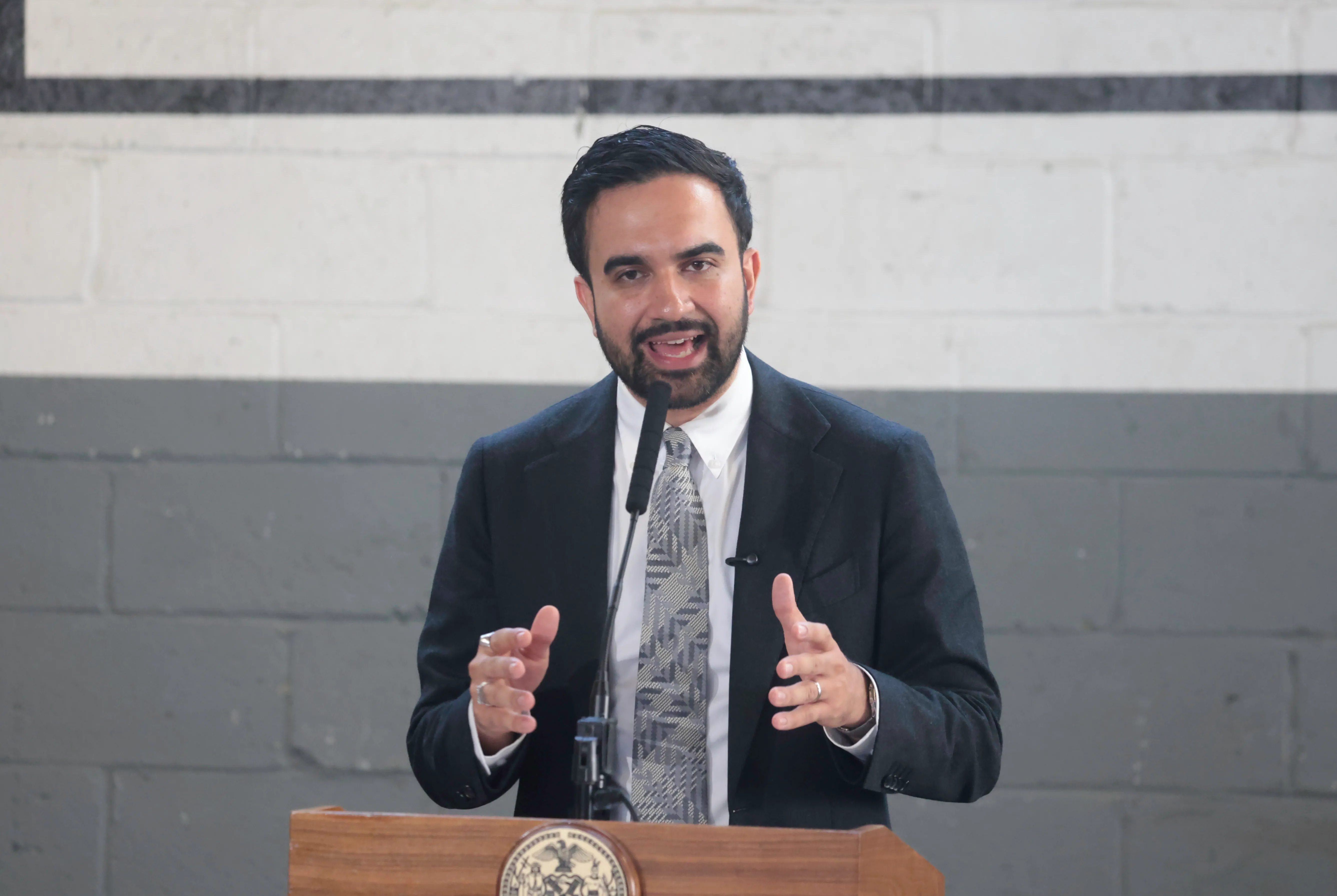 Mayor Zohran Mamdani in a suit speaks at a podium.