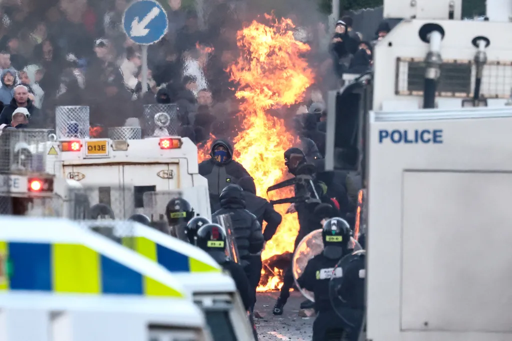 Police and protesters stand off as a fire burns between them.