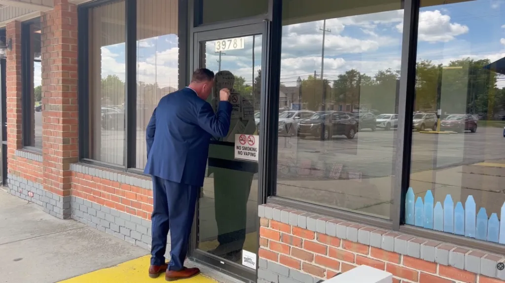 Michigan Rep. Jason Woolford looks into the front door of a daycare in Clinton Township.