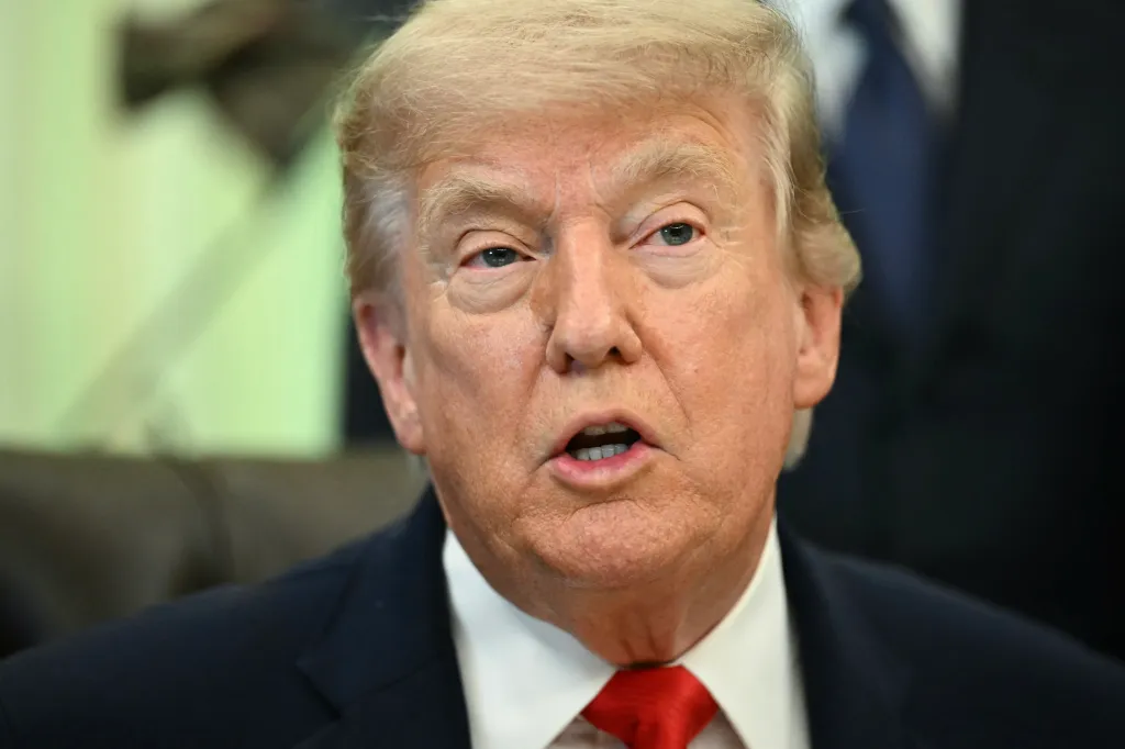 Close-up of Donald Trump speaking, wearing a suit and red tie.