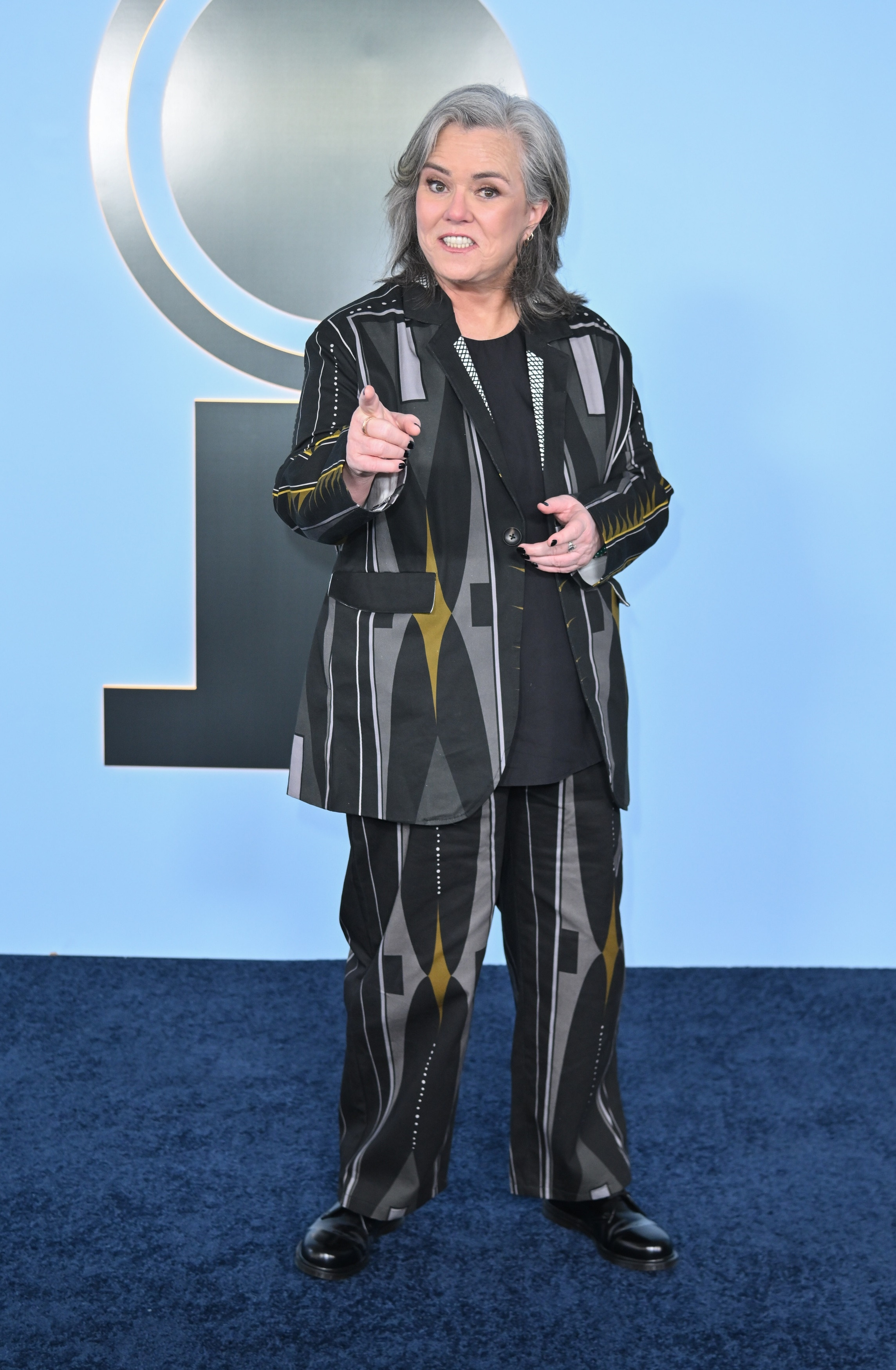 Rosie O'Donnell in a black, grey, and yellow patterned suit at the 79th Annual Tony Awards.