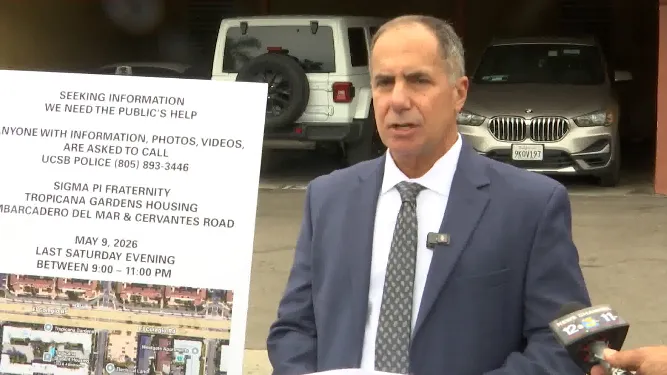 Attorney Tyrone Maho speaks about a reported rape at UCSB, with a sign in the foreground seeking public help.