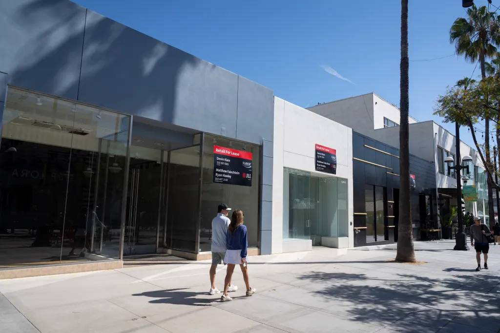 People walk past multiple empty retail spaces with 
