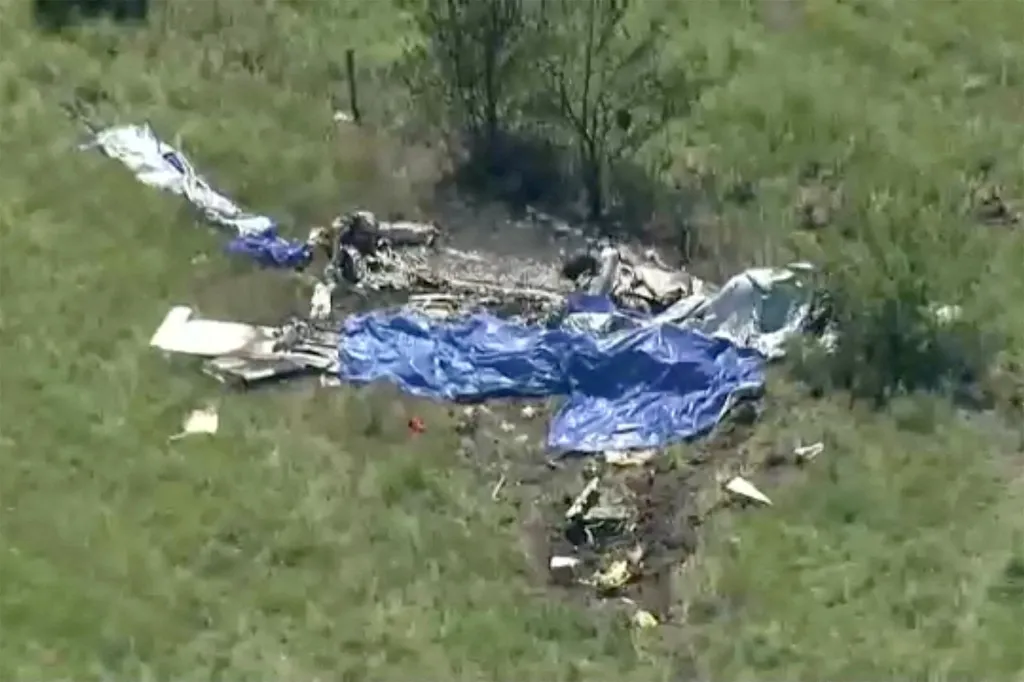 Wreckage of a plane crash in a field next to Butler Memorial Airport, with blue tarps covering parts of the debris.