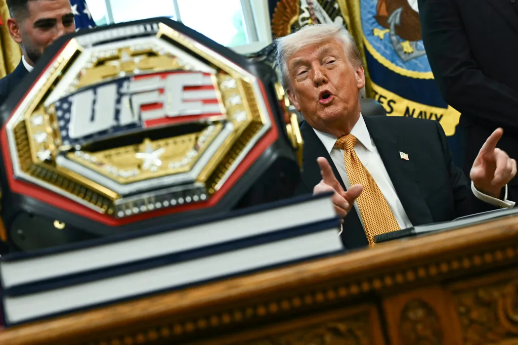 Donald Trump speaking with a UFC championship belt in the foreground.