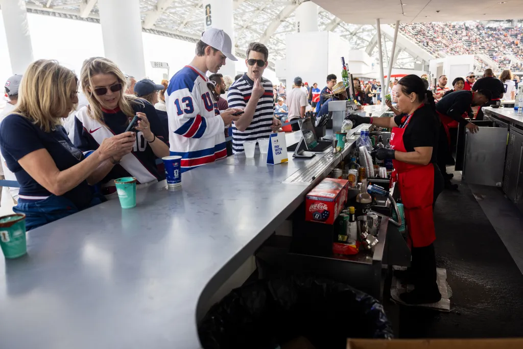 Fans buying snacks and beverages from a concession stand at a FIFA World Cup match.