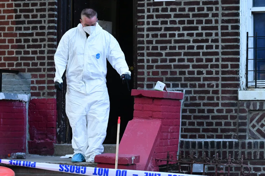 Forensic investigator in a white protective suit on a porch.
