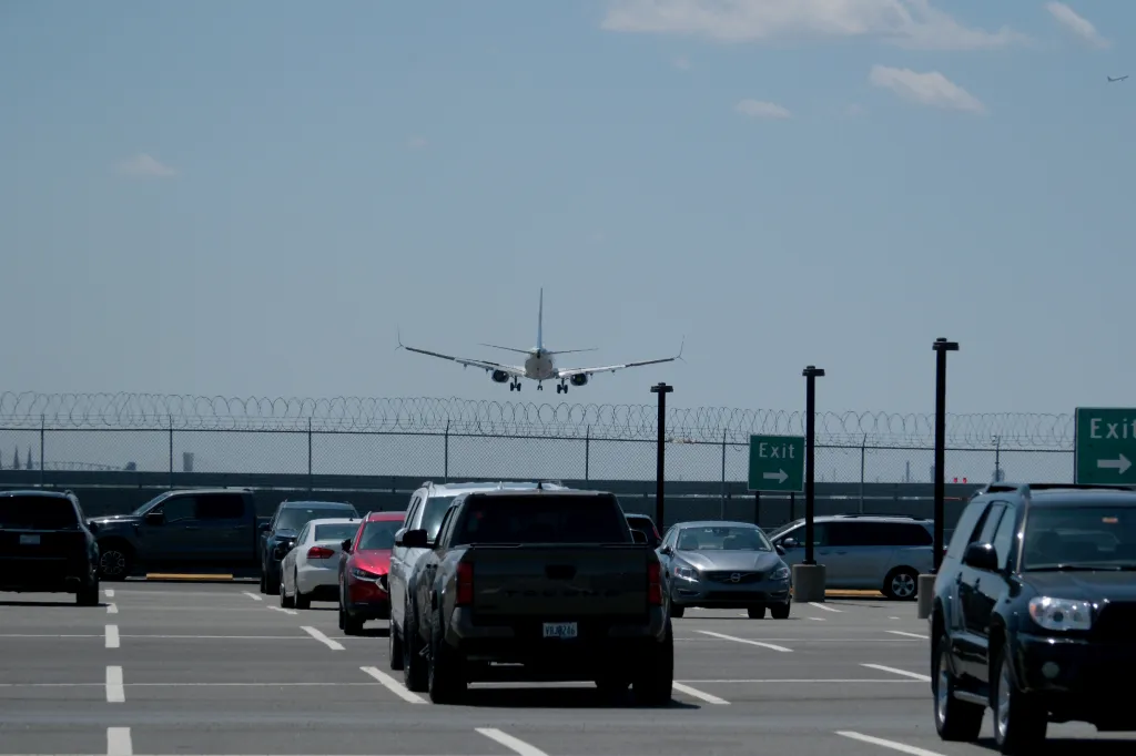 A United Airlines jetliner lands on a runway near a parking lot.