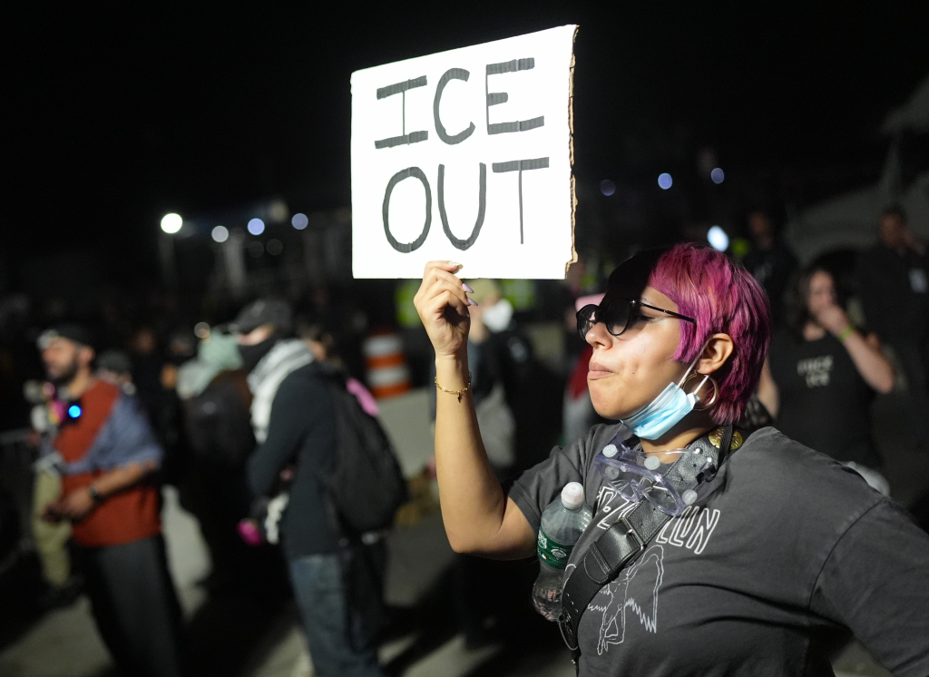 A protestor with pink hair holds a sign that reads 
