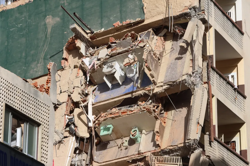 Damage to a multi-story building, showing exposed bathroom fixtures and rubble after a 7.2 magnitude earthquake in Venezuela.