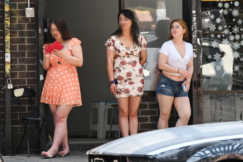 Three women stand outside a suspected sex shop on Roosevelt Avenue in Crotona, Queens, New York.