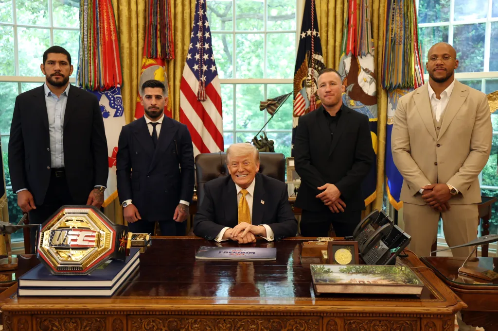 Donald Trump poses for a photo with four MMA fighters and a championship belt.
