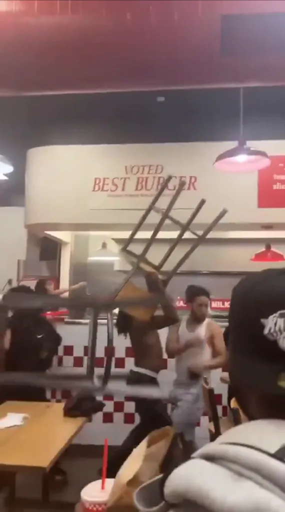 Man swinging a chair at another man inside a restaurant.