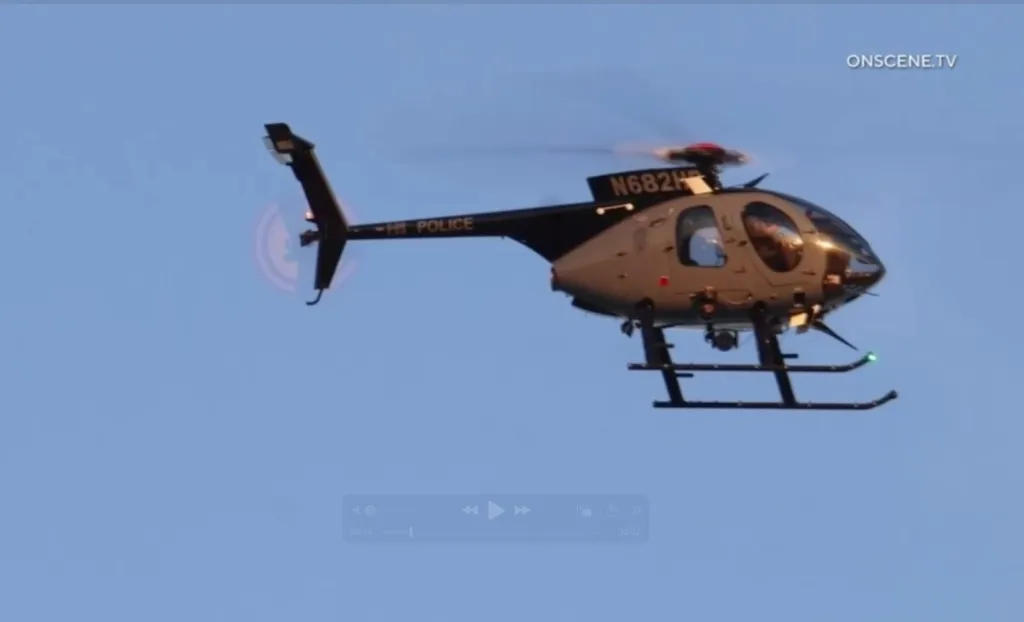 A police helicopter with the tail number N682H flying against a clear blue sky.