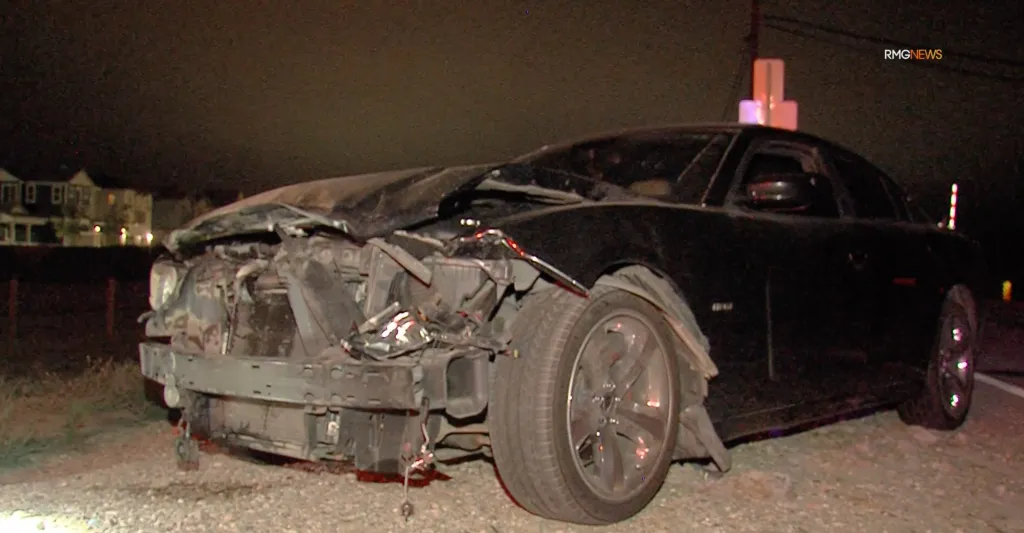 A black Dodge Charger with significant front-end damage after colliding with a bear.