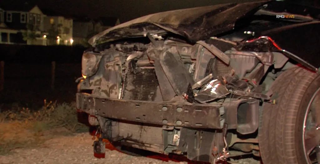 A black Dodge Charger with significant front-end damage after colliding with a bear.