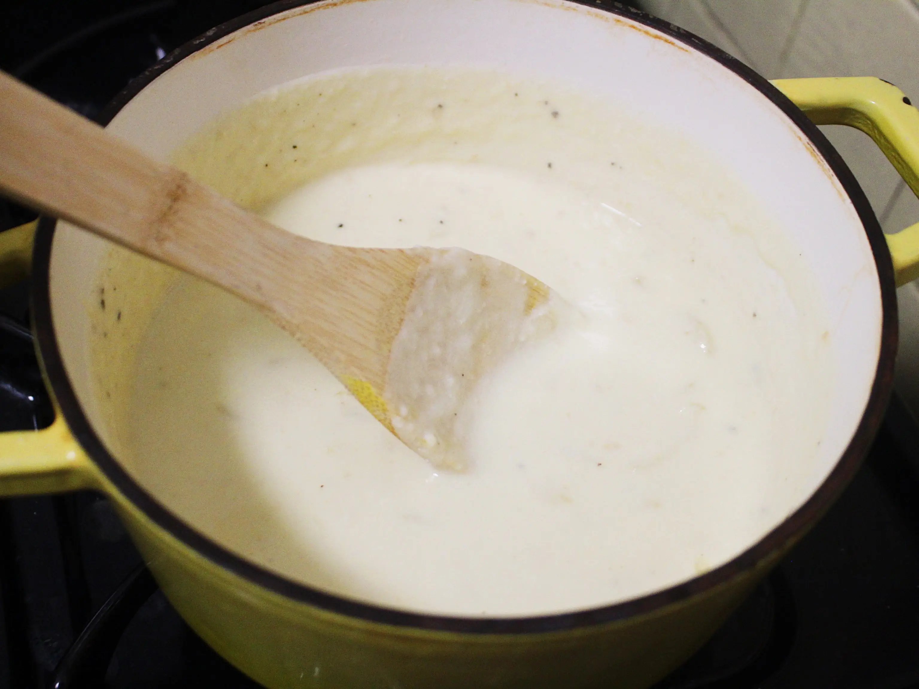 cheese sauce with wooden spoon on the stove