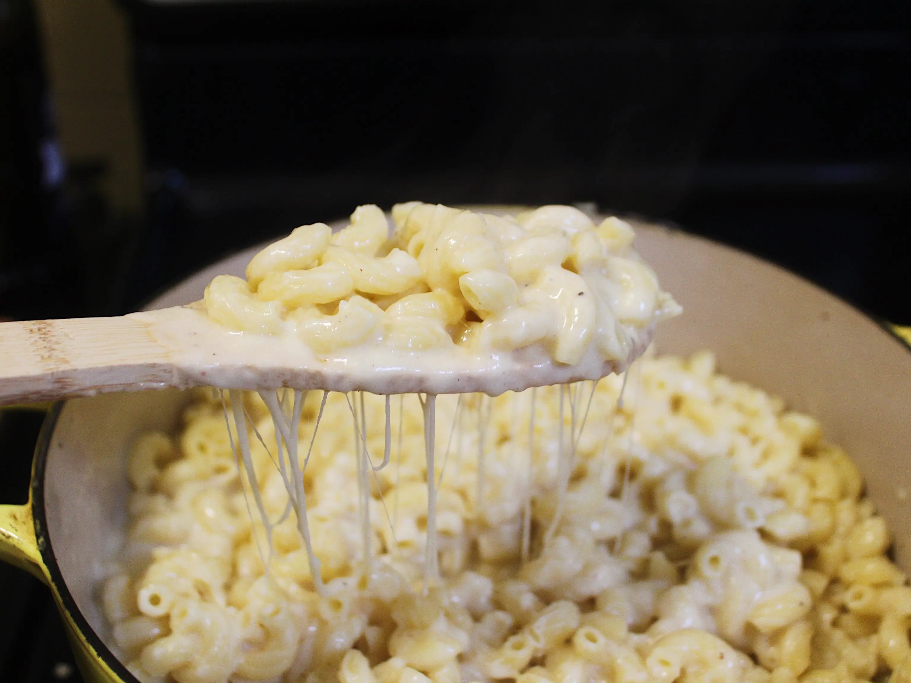 macaroni mixed with cheese sauce and a wooden spoon