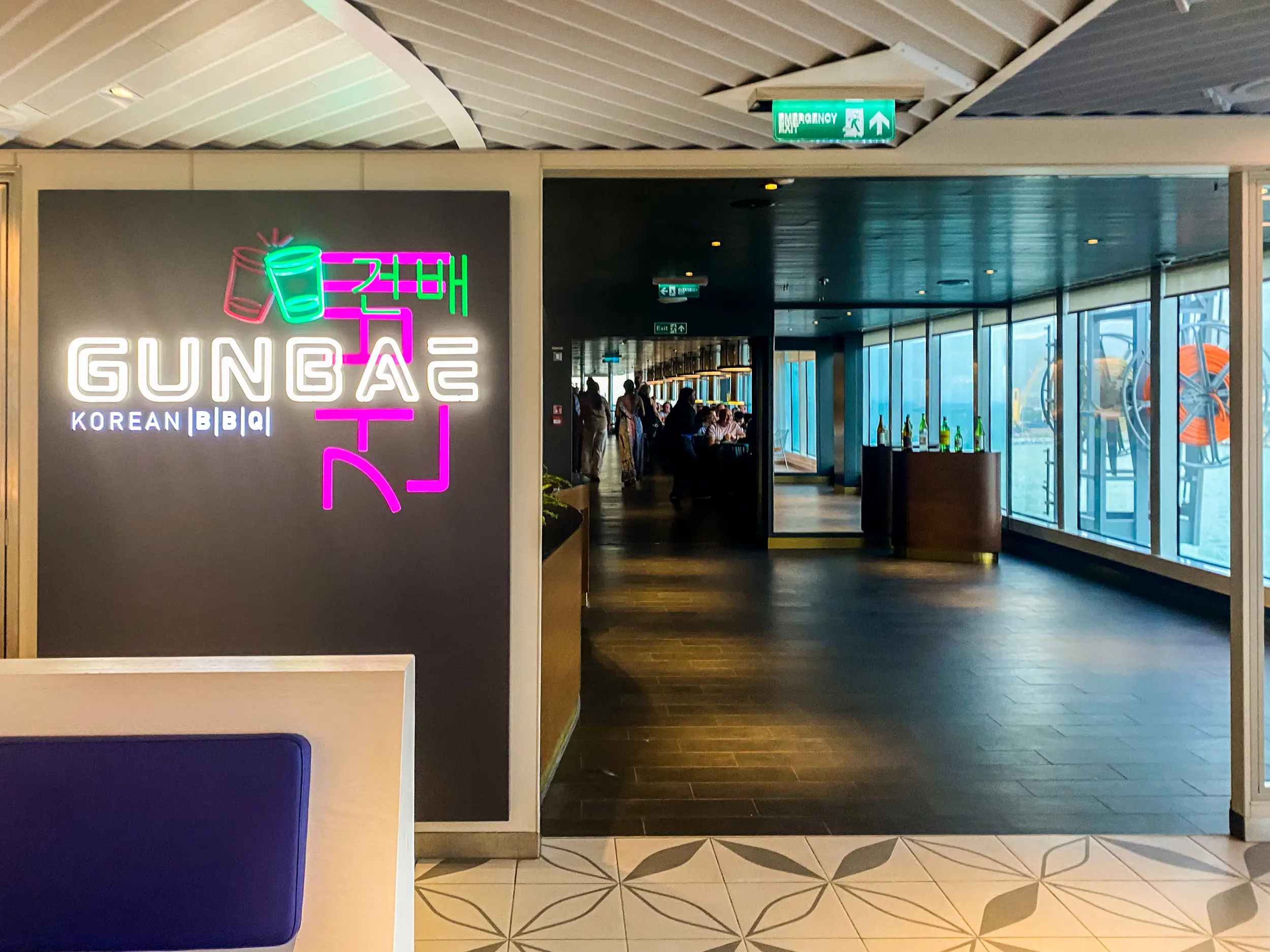 The entrance to a restaurant called Gunbae with a neon sign on the left and a view of the dining room on the right