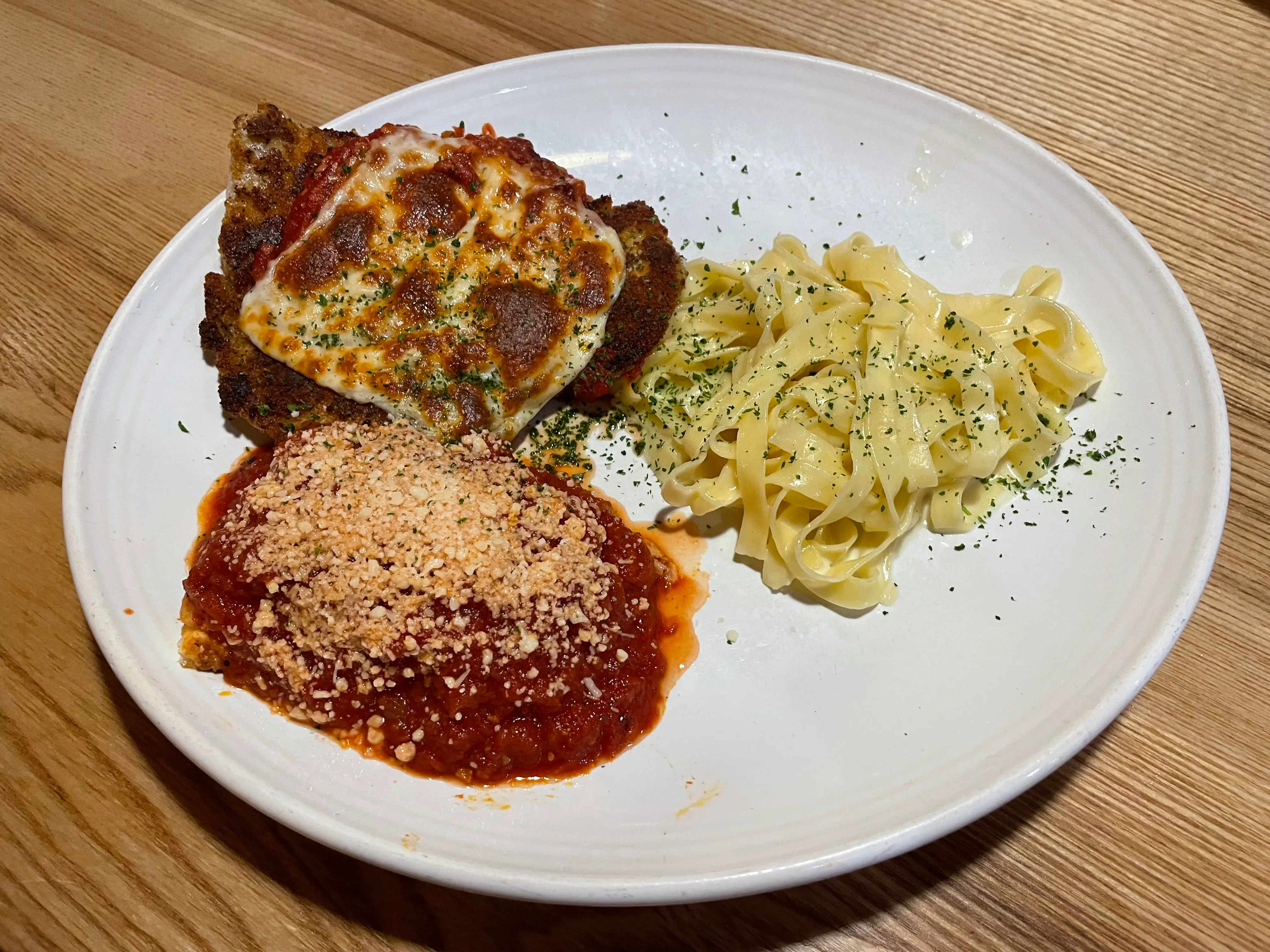 A plate with lasagna, pasta, and chicken Parmigiana.