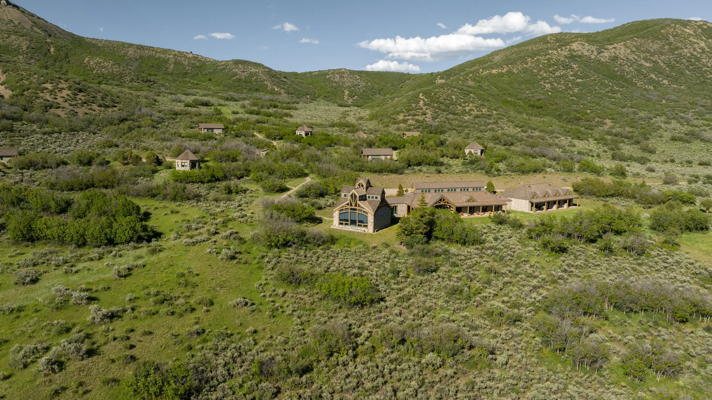 An aerial shot of some buildings surrounded by green hills.