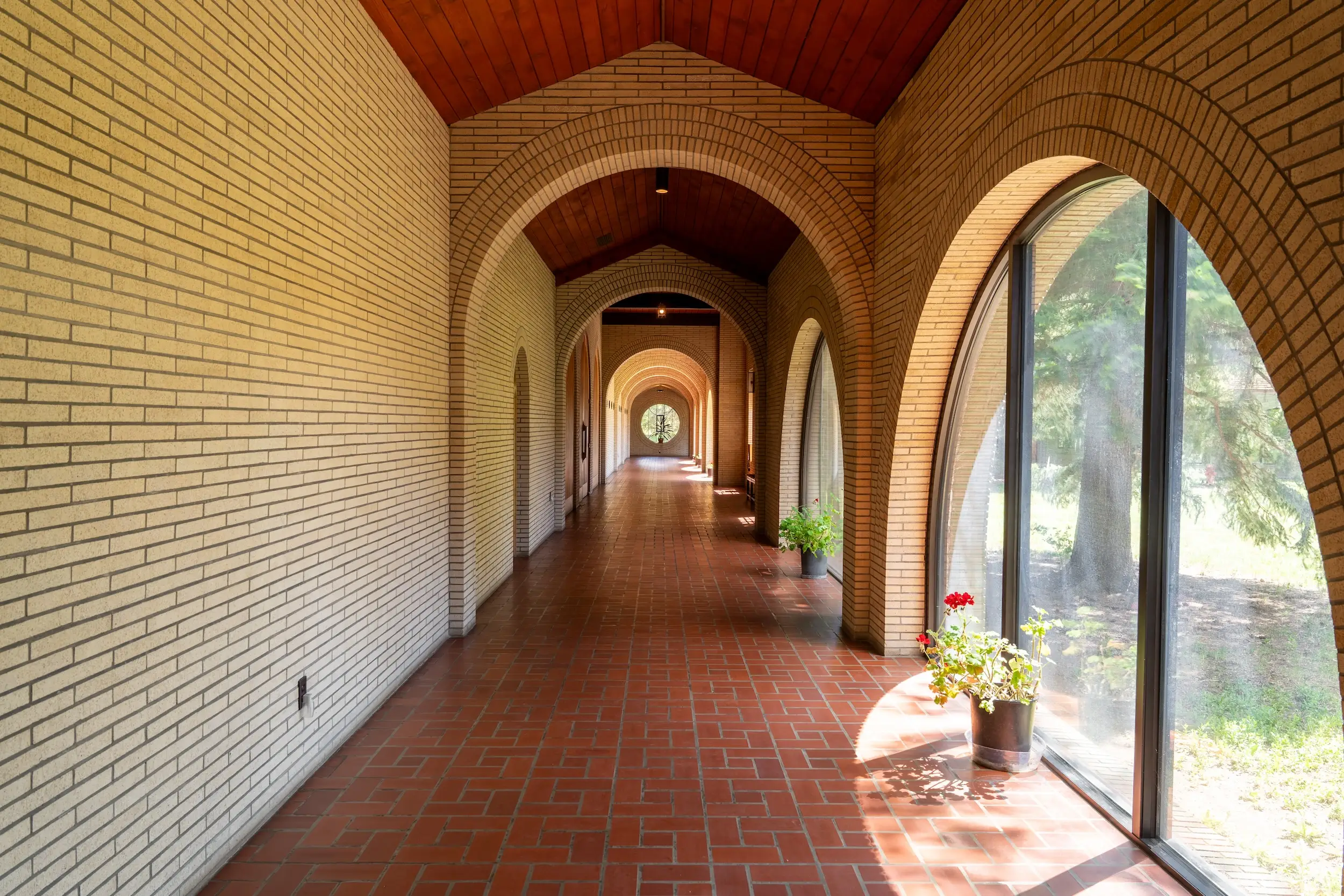 A hallway with arched windows along one side of it and a circle-shaped window at the end.