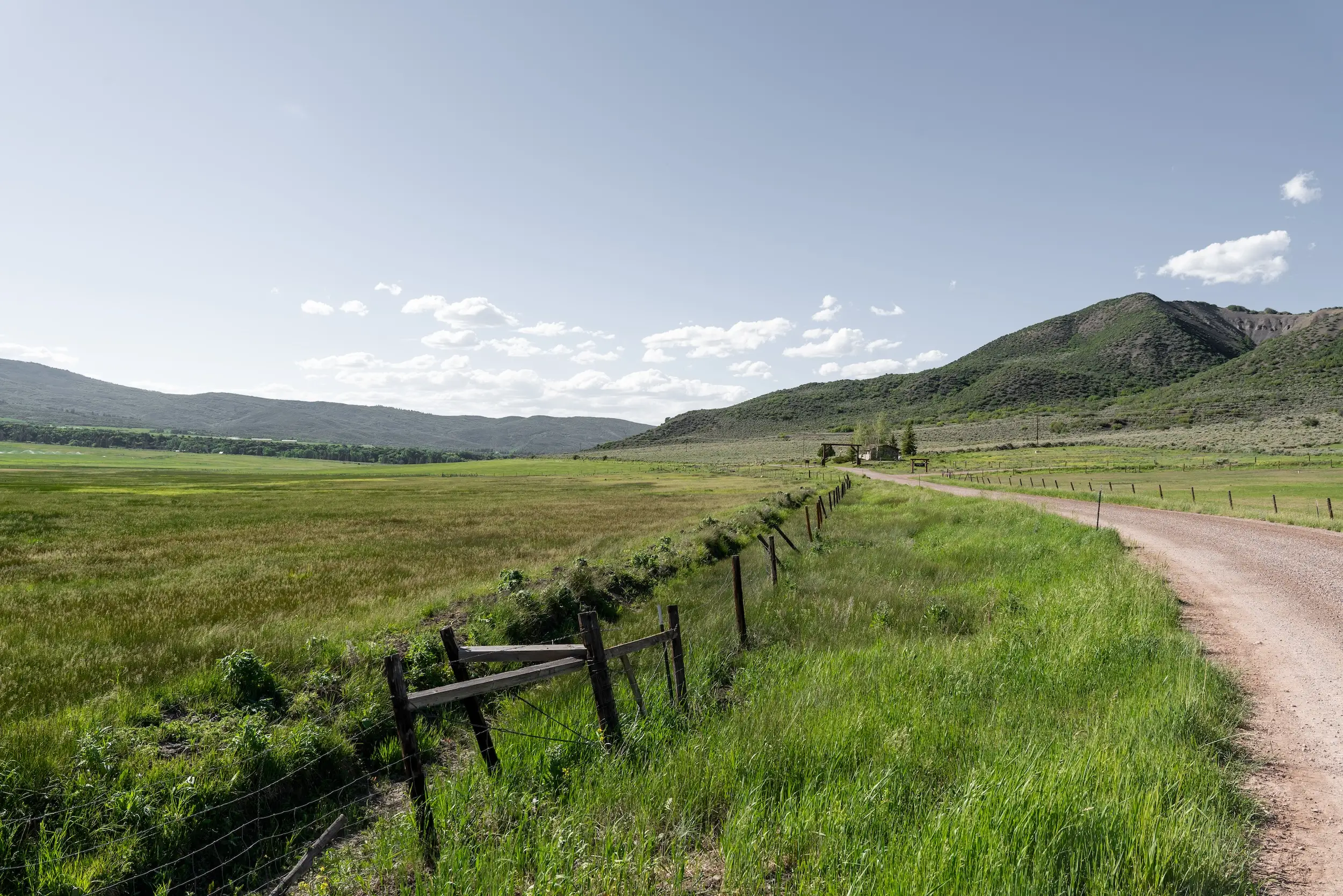 A wide green valley with a path on the right.