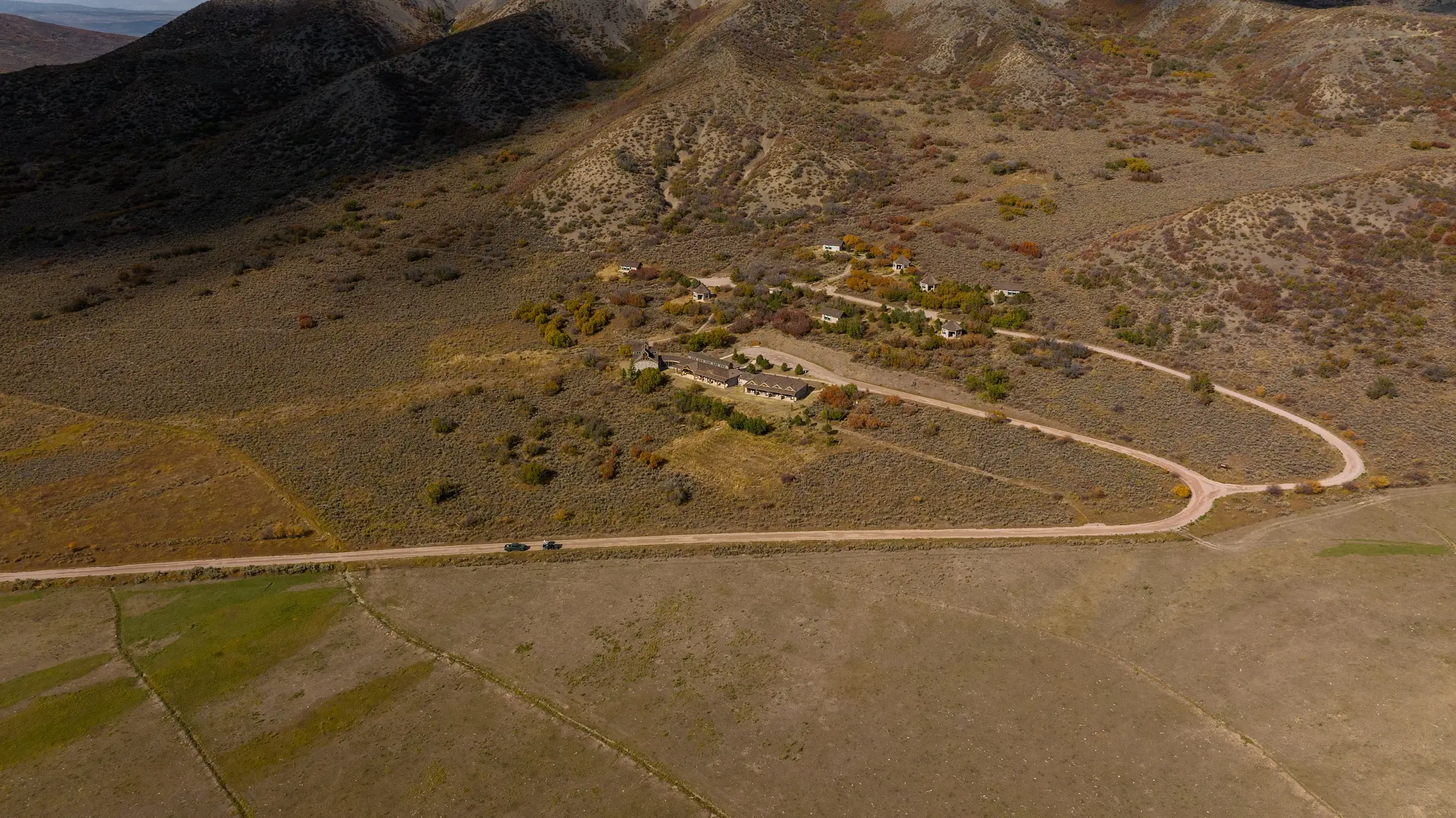 An aerial shot of some buildings on a spacious piece of land between hills.