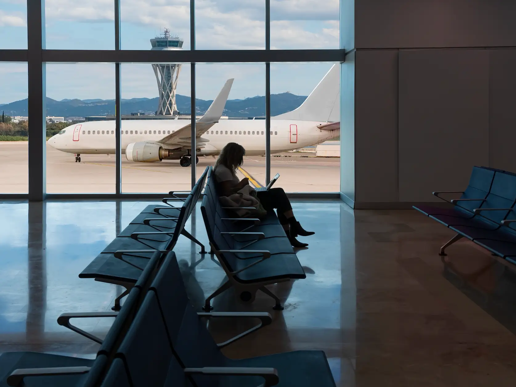 someone sitting in an uncrowded airport by a window